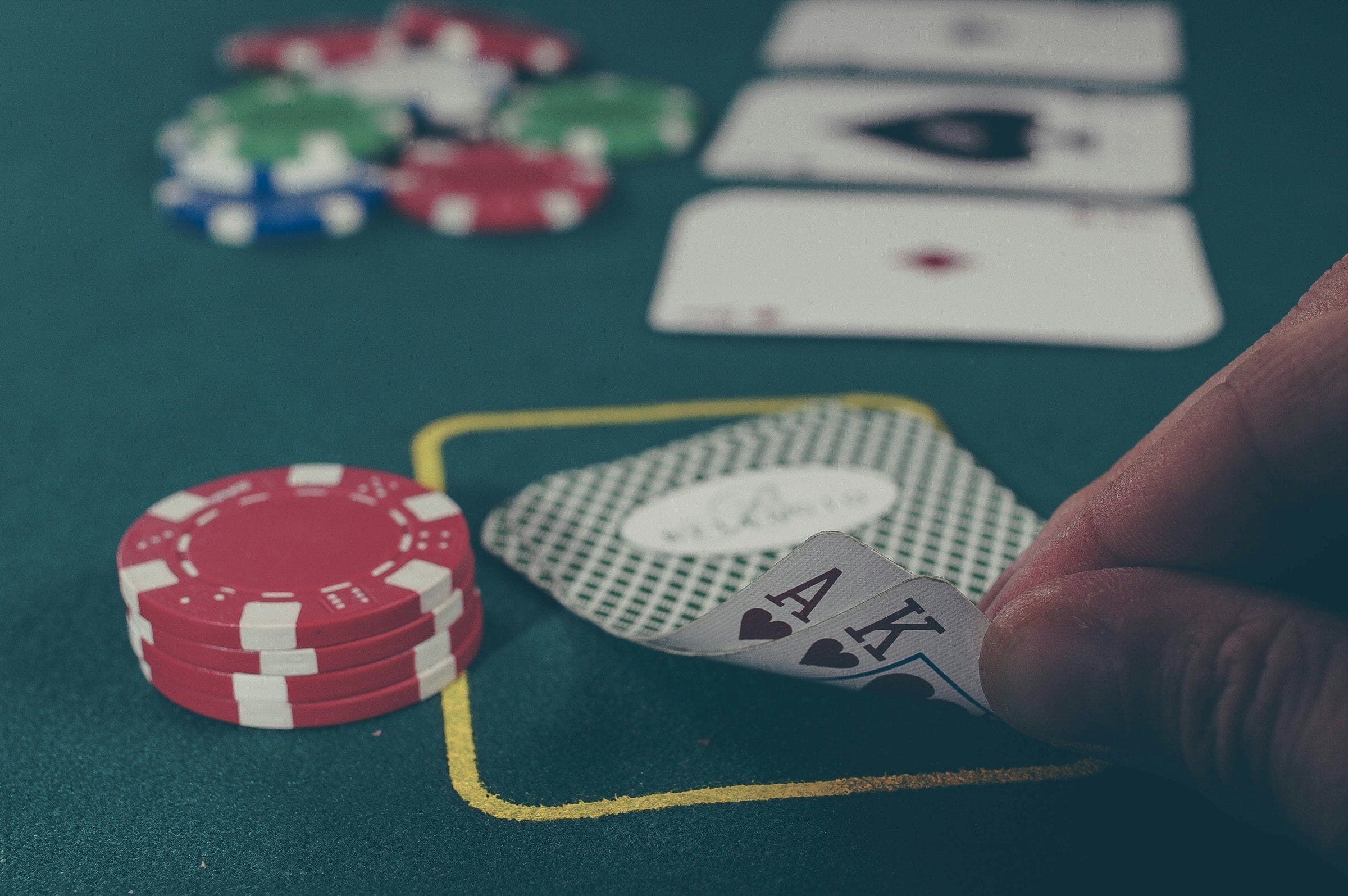 A player's hand holding an ace and a king at a poker table